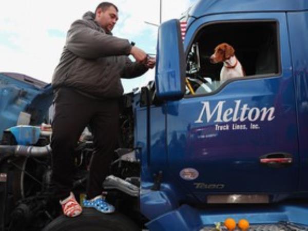 Truck driver Johnny Jenkins, from Georgia, attaches an American flag to his side view mirror as Jenkins and his dog Molly prepare to depart for Washington, DC to protest COVID-19 mandates on February 23, 2022 in Adelanto, California.
