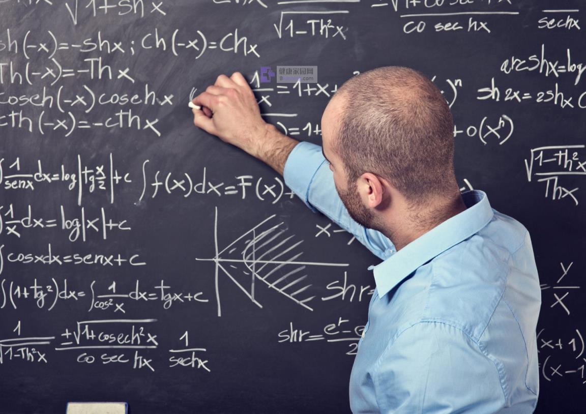 Man in blue shirt writing math o<em></em>nto a black chalk board.